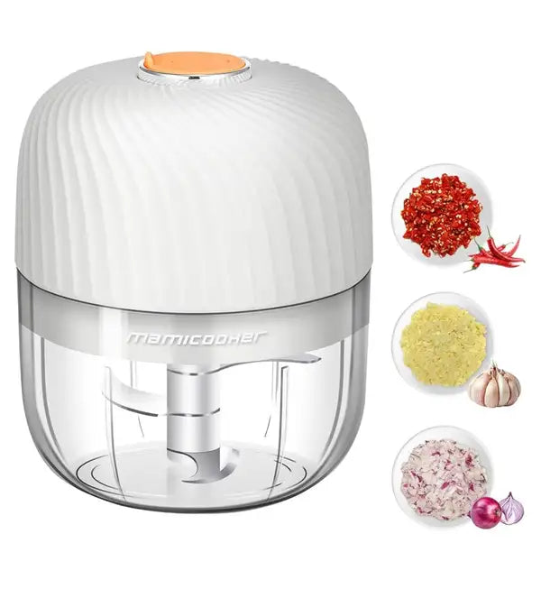 Electric mini garlic chopper with transparent bowl and stainless steel blades, surrounded by chopped garlic, onion, and chili peppers.